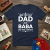 I Have Two Titles Dad and Baba And I Rock Them Both quote on a navy blue t-shirt, white bold