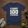 Navy t-shirt with bold white text "I LOST 100 POUNDS" celebrating a weight loss milestone