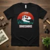 Black t-shirt with "I Love Dinosaurs" text above a T-Rex skull graphic and a vintage sunset background
