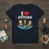 T-shirt with "I Love Otters" text and a heart, featuring three cartoon otters swimming in water