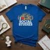 Blue t-shirt with white text "I Love Social Studies" and a graphic featuring a heart, globe, and educational icons