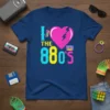 I Love The 80's t-shirt with a cracked heart, vintage phone, and cassette tape graphics in retro colors