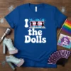 Blue t-shirt with white text "I love the Dolls" and silhouettes of dancers in front of a trans flag background