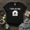 Black t-shirt with white text "I miss my dog" above a house graphic with a dog silhouette and a red