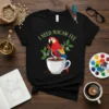 Black t-shirt with "I Need Macaw Fee" text and a colorful macaw sitting on a coffee cup