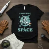 Black t-shirt with "I Need More Space" text, astronaut riding a T-Rex on a rocket, and planets in a retro