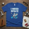Blue t-shirt with "I NEED SPACE" text and an astronaut riding a bicycle on a rocket through space
