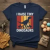 Navy t-shirt with "I Raise Tiny Dinosaurs" text and silhouette of a T-Rex with chicks