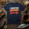 Navy t-shirt with "I Rented This Hooker" text and a red arrow graphic, featuring fishing gear background