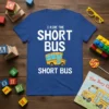 Blue t-shirt with white text "I RIDE THE SHORT BUS" above a cartoon yellow short bus, with "SHORT BUS" below