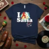 Navy blue t-shirt with "I Salsa" text and graphic of two dancing figures in red and white, surrounded by musical