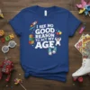 I See No Good Reason To Act My Age quote t-shirt with a playful design featuring a rocket, blocks, and