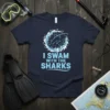 I Swim With The Sharks text and shark graphic on a navy blue t-shirt, designed for ocean lovers and divers