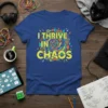 Yellow text "I THRIVE IN CHAOS" with a colorful, abstract spiral graphic on a royal blue t-shirt