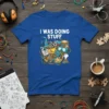 Blue t-shirt with white text "I Was Doing Stuff" and a colorful collage of creative and technical items