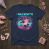 T-shirt design with text "I WAS NOW I'M" above a pink axolotl wearing sunglasses riding donuts, numbers 6 and 7