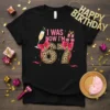 I WAS NOW I'M 67 text with leopard print numbers, champagne glass, and gift boxes graphic on a black t-shirt