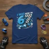 Blue t-shirt with "I WAS NOW I'M 67" text, a blue race car, checkered flags, and racing theme graphics