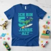 Ich bin 5 Jahre alt t-shirt with a green dinosaur wearing a helmet and goggles riding a rocket surfboard. The