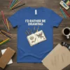 T-shirt with "I'd Rather Be Drawing" text and illustration of an open sketchbook with art supplies and a bird