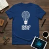 Blue t-shirt with white text "IDEA? IGNITE" and a white graphic of a lightbulb filled with a brain