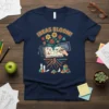 Navy t-shirt with "IDEAS BLOOM!" text above an open book, digital tablet, and colorful flowers, symbolizing creative growth
