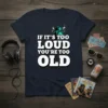 Bold white text "IF IT'S TOO LOUD YOU'RE TOO OLD" on a navy t-shirt, with teal speakers graphic above