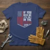 If You Need Me I'll Be In The Garage quote on a navy t-shirt with American flag design elements and