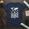 Navy t-shirt with "I'm Doing World Quests" text and a world map graphic featuring landmarks and travel icons