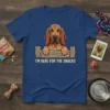 Bloodhound dog peeking over a wooden fence with text "I'm Here For The Snacks" on a blue t-shirt