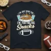 I'm Just Here For The Snacks text and football graphic on a dark t-shirt, perfect for game day