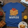 Blue t-shirt with "I'm Just Here For The Waffles" text and cartoon stack of waffles with strawberries and syrup graphic