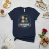 Graphic t-shirt design with text "I'm My Mother-In-Law's Favorite Child" featuring a cartoon grandmother and grandchild holding hands