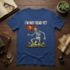 I'm Not Dead Yet t-shirt design featuring a skeleton in a pilot helmet holding a flag with a skull emblem