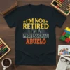 Text design "I'm Not Retired I'm A Professional Abuelo" in distressed yellow and orange font on a black t-shirt