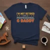 I'm Not Retired I'm A Professional G Daddy T-Shirt with bold orange and yellow text on a navy blue shirt