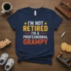 I'm Not Retired I'm a Professional Grampy quote on a navy blue t-shirt with orange and yellow text