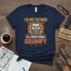 Navy blue t-shirt with "I'm Not Retired I'm A Professional Grumpy" text and a cartoon grumpy man illustration