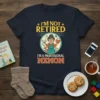 T-shirt with "I'm Not Retired I'm A Professional Memom" text and graphic of a woman with books, baby bottle, dog