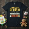 I'm Not Retired I'm A Professional Nanny text design with baby bottle and blocks graphic on a dark t-shirt