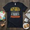 I'm Not Retired I'm A Professional Peepaw T-Shirt with yellow and orange text and cartoon graphics of grandparents and a