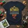 Dark heather t-shirt with yellow and orange text reading "I'm Not Retired I'm A Professional Pop" with a crown graphic