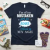 Navy t-shirt with white and blue text reading "I'm often Mistaken for an Adult Because of MY AGE" in a
