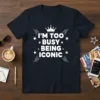 I'm Too Busy Being Iconic quote with a crown graphic on a navy t-shirt