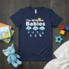 Navy t-shirt with "i'm With the Babies" text and cute baby-themed graphics including clouds, pacifiers, and a baby bottle