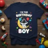I'm The Birthday Boy astronaut t-shirt design with a child astronaut sitting on the moon holding balloons, colorful planets, and