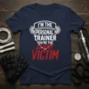 Navy t-shirt with white text "I'm The Personal Trainer" and red text "VICTIM" with "CLIENT" crossed out, featuring barbell graphic