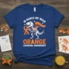 Leukemia Awareness T-Shirt with a T-Rex skeleton wearing an orange ribbon, text reads 'In March We Wear Orange Leukemia Awareness'