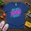 Neon 'In My 1989 Era' text design on a blue t-shirt, with retro 80s geometric accents