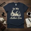 In My Author Era t-shirt design with open book, quill, moon, stars, and coffee cup